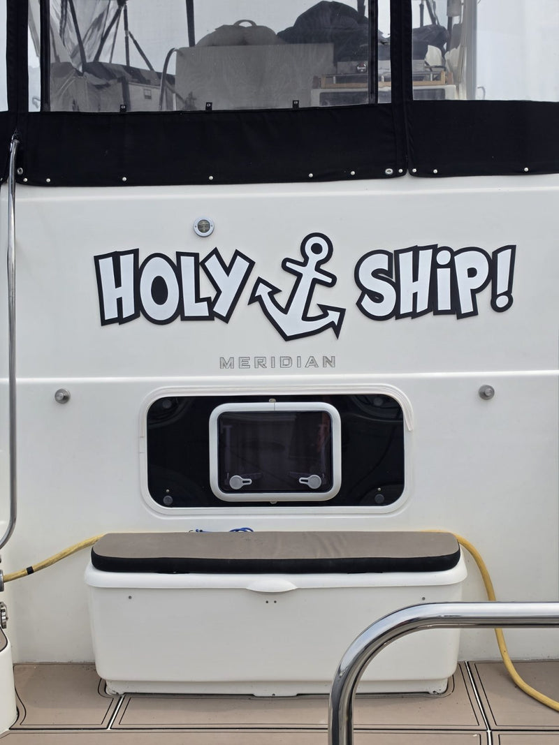 Holy Ship boat name in white outlined lettering with an anchor, on a cream transom